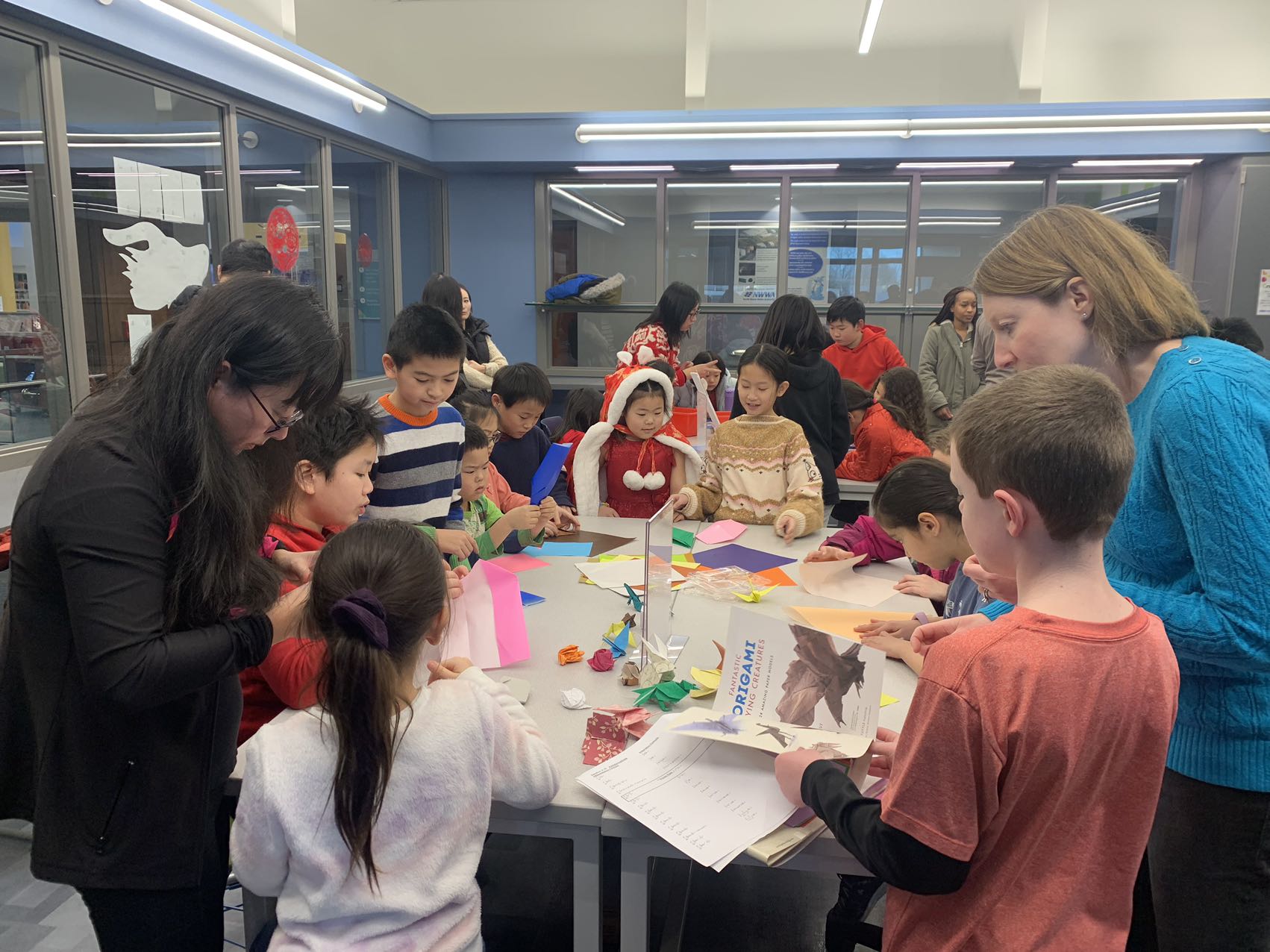 A group of children learning how to do origami at the origami table.